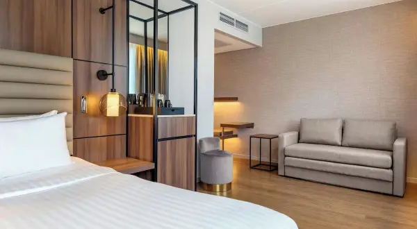 Ett modernt hotellrum på AC Hotel Solna med en bekväm säng, soffa och stilren inredning.
