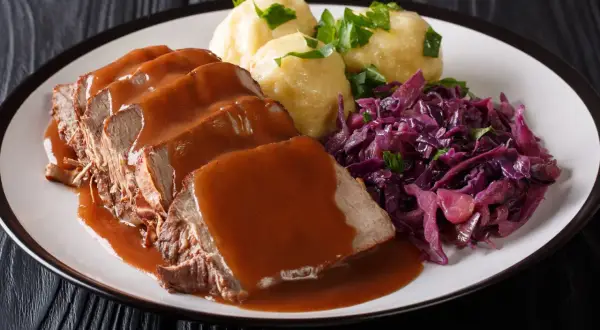 Ein Teller mit saftigem Sauerbraten, Klößen und Rotkohl. Perfekt für die Schwangerschaft, wenn man Lust auf Hausmannskost hat.