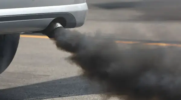 El tubo de escape de un coche emite una densa nube de humo negro, contaminando el aire.