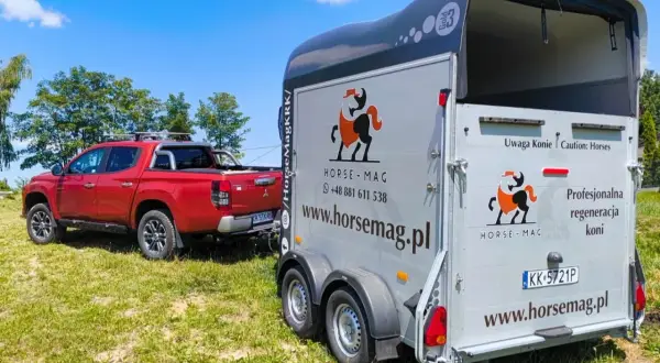 Czerwony pickup holuje przyczepę do przewozu koni. Na przyczepie logo Horse-Mag i napis "Uwaga Konie".