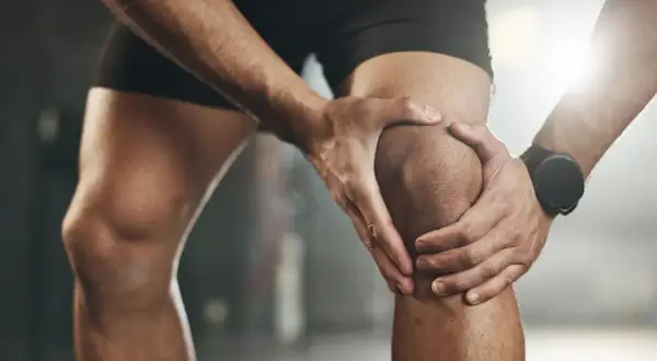 Sportler hält schmerzendes Knie, deutet auf eine mögliche Kreuzbandriss Schwellung hin.
