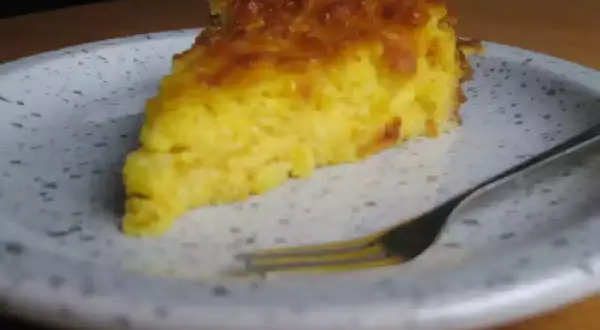 Una rebanada de torta de maiz dorada y esponjosa en un plato, lista para ser disfrutada con un tenedor.