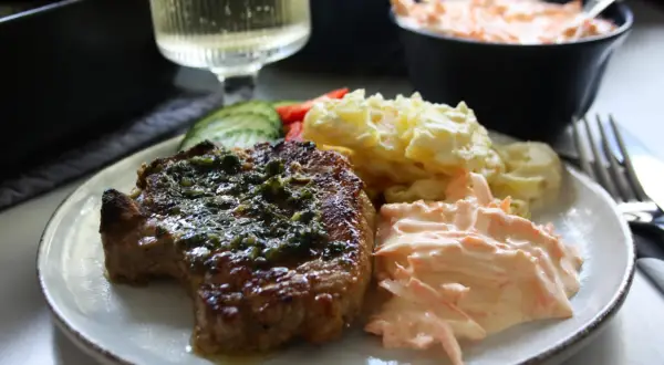 En saftig kotlett i ugn med örter, serverad med potatisgratäng och en krämig morotsallad. En perfekt middag!