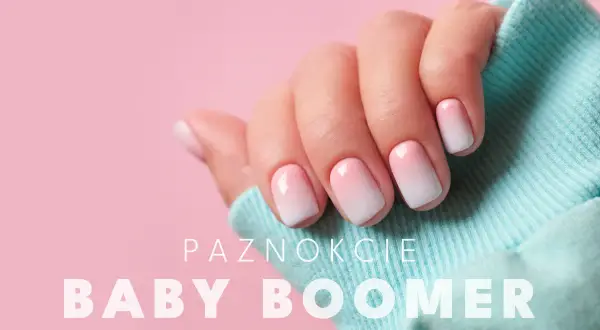 Dłoń z paznokciami w stylu baby boomer, delikatny gradient różu i bieli na jasnoróżowym tle.