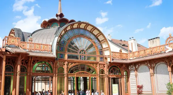L'architecture Art Nouveau du Palais Lumière à Évian-les-Bains, avec ses vitraux colorés et sa structure en bois, sous un ciel bleu.