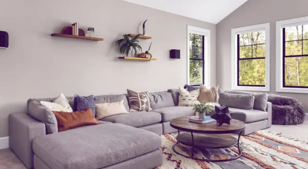 Gemütliches Wohnzimmer mit großem Ecksofa, Kaffeetisch und einem auffälligen Teppich im Boho-Stil, der den aktuellen Teppich Trend widerspiegelt.
