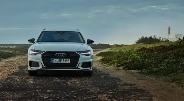 Audi A6 Avant blanche sur une route côtière. La plaque d'immatriculation "IN BE 719E" permet de connaître le modèle de voiture.