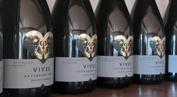 Bottiglie di Vives Passerina Brut, un vino fermo o frizzante, con etichetta a forma di cuore con teschio dorato.