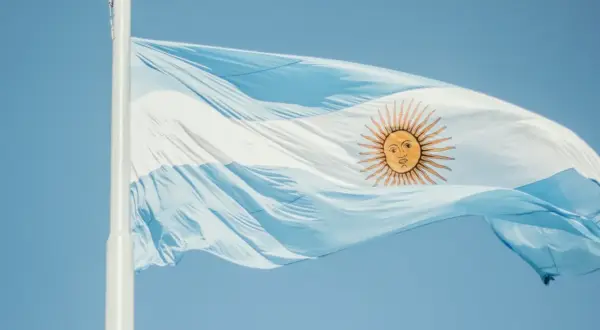 Flaga Argentyny powiewa na wietrze na tle błękitnego nieba.