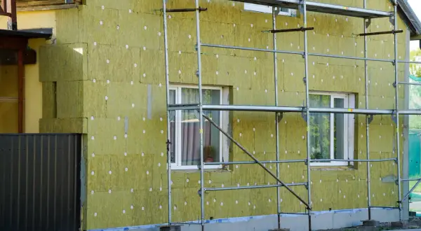 Dom w trakcie termomodernizacji, ocieplany wełną mineralną. Widać rusztowania i fragmenty starego muru pruskiego.