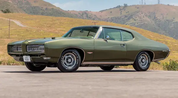 Zielony Pontiac GTO z 1969 roku na tle wzgórz. Klasyk amerykańskiej motoryzacji.