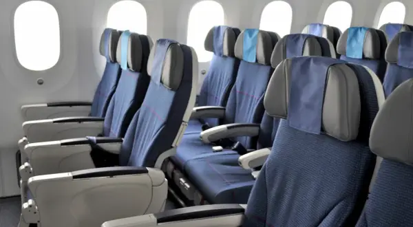 Reihe von blauen Flugzeug Sitze mit grauen Kopfstützen und kleinen blauen Kissen.