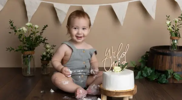 Glad baby firar 1-årsfotografering med tårta. Tips för en lyckad fotografering: lekfull miljö, tårta och glada barn.