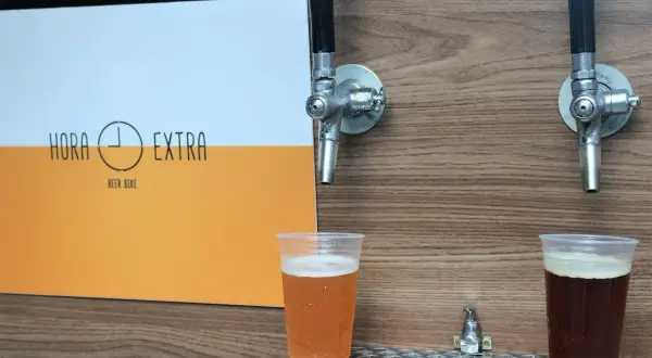 Dwa piwa w plastikowych kubkach pod kranikami. Jedno jasne, drugie ciemne. Logo "Hora Extra Beer Bike" z boku. Idealne na piwo bez chmielu.