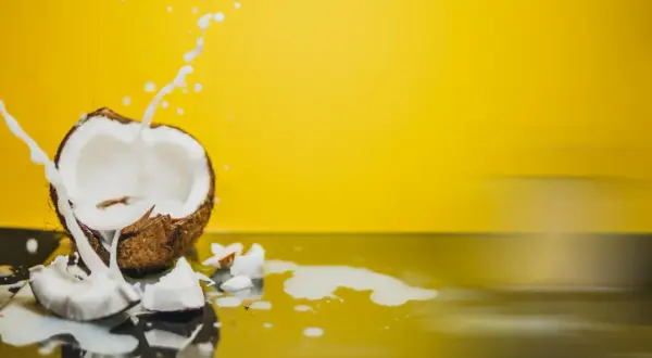 Éclaboussures de lait de coco sur fond jaune vif, révélant la texture crémeuse du lait de coco.
