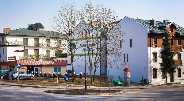 Sanatorium & pensjonat Zbyszko, z restauracją, zaprasza gości. Budynki z balkonami i zielonym dachem.