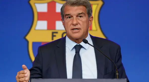 Prezydent FC Barcelona przemawia na tle herbu klubu, omawiając, ile Barcelona ma długu.