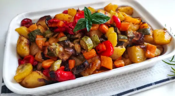 Un plat coloré de recette caponata sicilienne traditionnelle au four, avec des légumes rôtis et une touche de basilic frais.