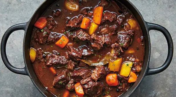 En mustig kalops i gjutjärnsgryta, perfekt för ett klassiskt kalops recept. Kött, morötter och potatis i en mörk sås.