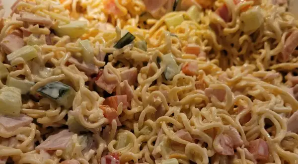 Pyszna sałatka z zupek chińskich z szynką, ogórkiem i pomidorem, polana kremowym sosem.