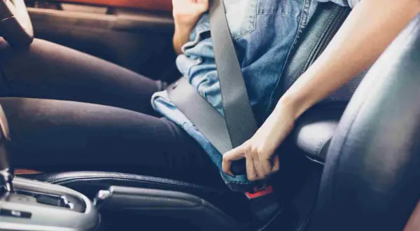 Persona abrochándose el cinturón de seguridad, un gesto esencial para la seguridad en la circulación vial.