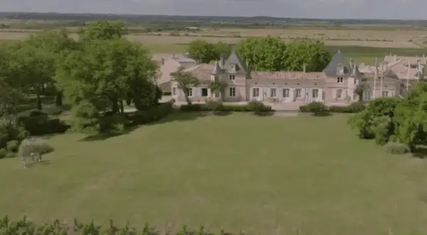 Un magnifique château bordelais, typique de la route des châteaux du Médoc, se dresse au milieu de vignes et d'arbres verdoyants.
