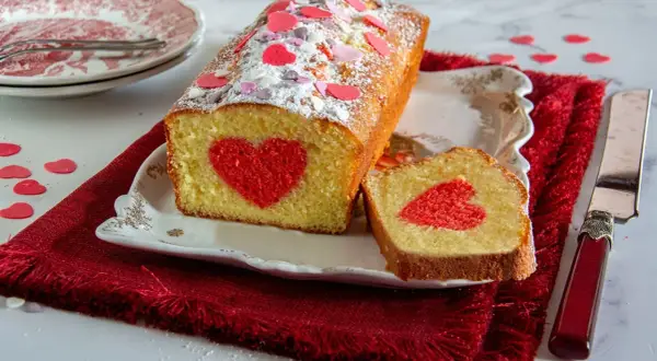 Plumcake farcito con un cuore rosso al centro, decorato con zuccherini a forma di cuore.