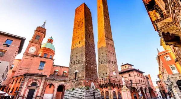 Le Due Torri svettano maestose nella piazza Maggiore di Bologna, con la Basilica di San Petronio sullo sfondo.