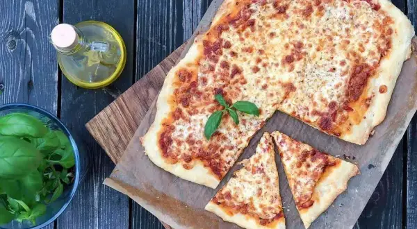 Pyszna pizza margerita z bazylią, oliwą i pomidorami. Idealna na letni wieczór.
