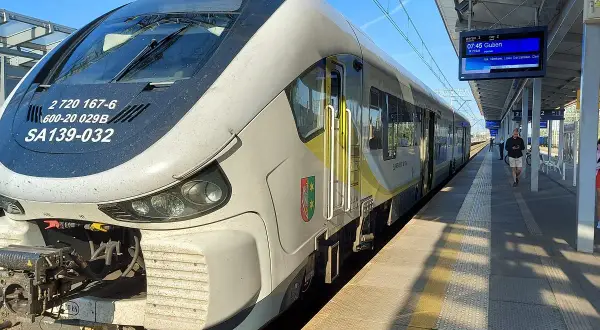 Pociąg SA139-032 na stacji, gotowy do odjazdu. Na tablicy informacyjnej widnieje kierunek Guben. Zielona góra łódź to symbol, który może kojarzyć się z podróżą.