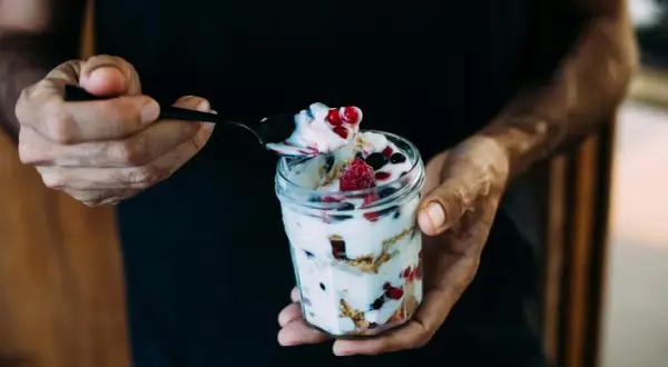 Ein Glas mit Magerquark, Beeren und Knuspermüsli. Perfekt für gesunde Magerquark Rezepte.