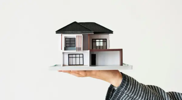 Modellino di casa moderna su mano, pronto per l'asseverazione contratto di locazione.