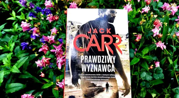 Prawdziwy Wyznawca" Jacka Carra, thriller w otoczeniu kwitnących kwiatów.