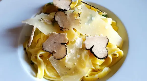 Tagliatelle z truflami ze słoika, posypane płatkami parmezanu. Luksusowy smak w każdym kęsie.