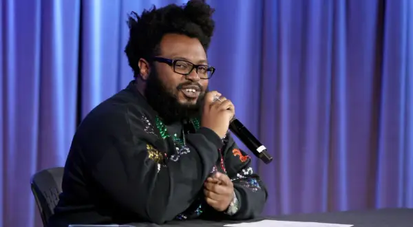 James Fauntleroy, a songwriter and producer, speaks into a microphone. His extensive James Fauntleroy discography is a testament to his talent.