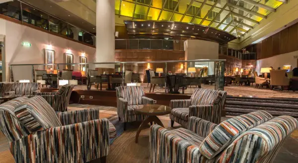 Przytulne fotele w paski w lobby hotelu Hyatt Warszawa, pod przeszklonym dachem.