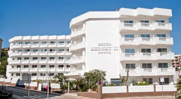 Hotel Bernatti, idealny na wakacje all inclusive w Barcelonie. Biały budynek z balkonami i widokiem na morze.