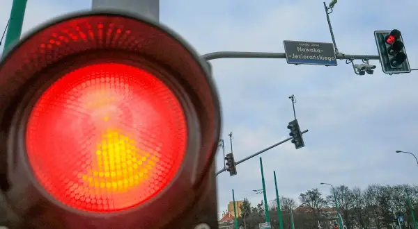 Czerwone światło na sygnalizatorze drogowym, a obok niego fotoradar na światłach. Uważaj, bo możesz dostać mandat.