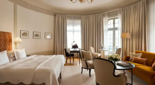 Ett elegant rum på Clarion Hotel Östermalm med en stor säng, soffa, skrivbord och vackra gardiner.
