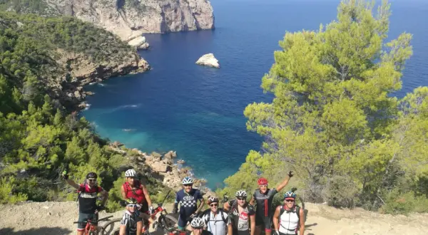 Grupo de ciclistas disfrutando de una ruta de ibiza en bicicleta con vistas espectaculares al mar Mediterráneo.