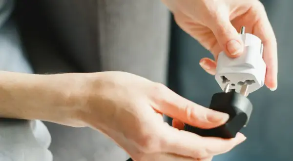 Ręce łączą adapter do gniazdka, przygotowując się do podróży do Włoch.
