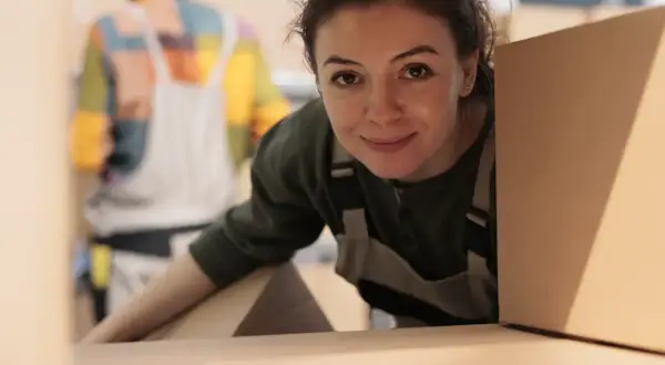 Donna sorridente con scatole, pronta per organizzare un trasloco senza stress.