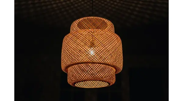 Pleciona, bambusowa lampa ruchoma rzuca na sufit cień przypominający siatkę.