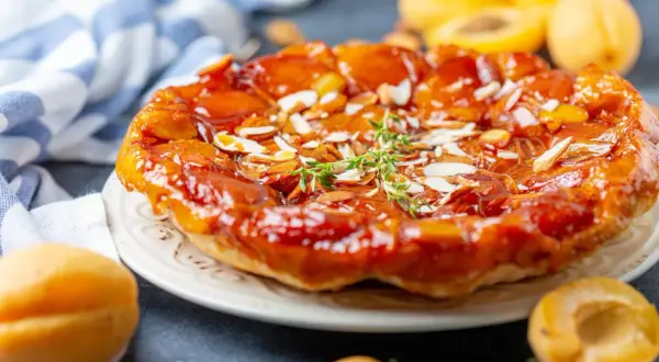 Tarte aux abricots caramélisée, garnie d'amandes effilées et d'une touche de thym frais. Un délice doré et gourmand.