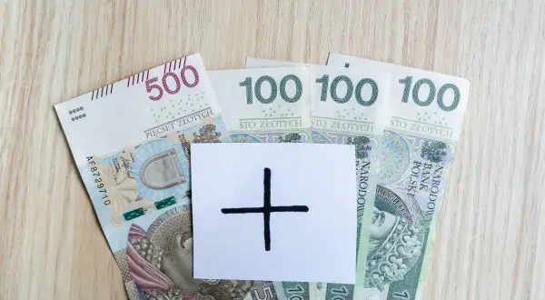 Polskie banknoty 500 i 100 zł. Na białej kartce symbol plusa, sugerujący, że 4200 brutto to dopiero początek.
