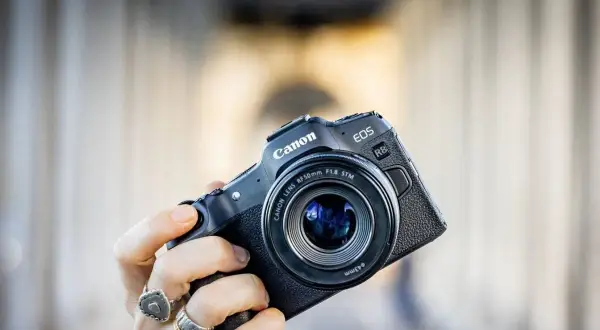 Mano che tiene una fotocamera Canon EOS R8 con obiettivo 50mm f/1.8 STM. Un modello compatto, ideale per chi cerca la qualità di un sensore canon apsc.