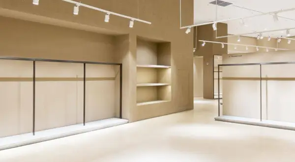 Interni di un locale commerciale in fase di ristrutturazione, con scaffalature vuote e illuminazione a faretti.