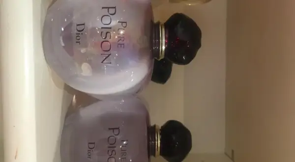 Dwa flakony perfum Pure Poison Dior 100ml, każdy z fioletową poświatą i czarnym korkiem.