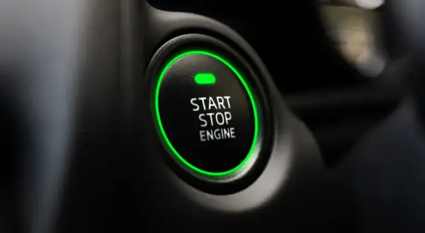 Przycisk "START STOP ENGINE" z zieloną obwódką, gotowy do odpalenia auta.
