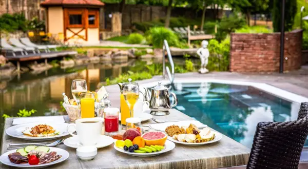 Petit-déjeuner copieux au domaine Moulin Ensisheim, avec vue sur la piscine et le jardin.